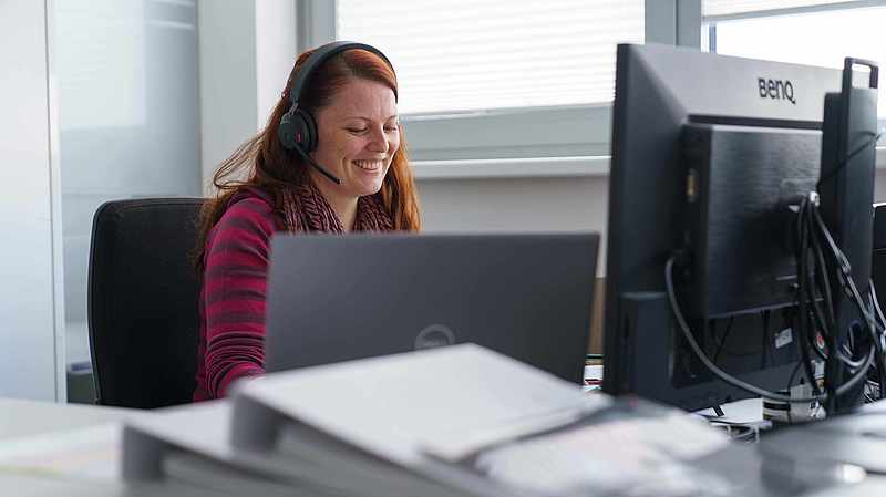 Kundenberaterin mit Headset am Schreibtisch