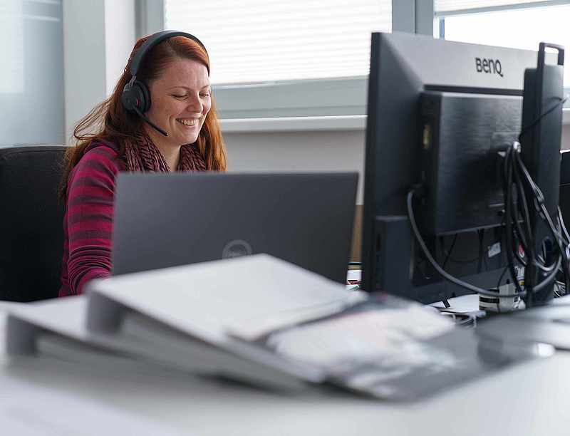 Kundenberaterin mit Headset am Schreibtisch