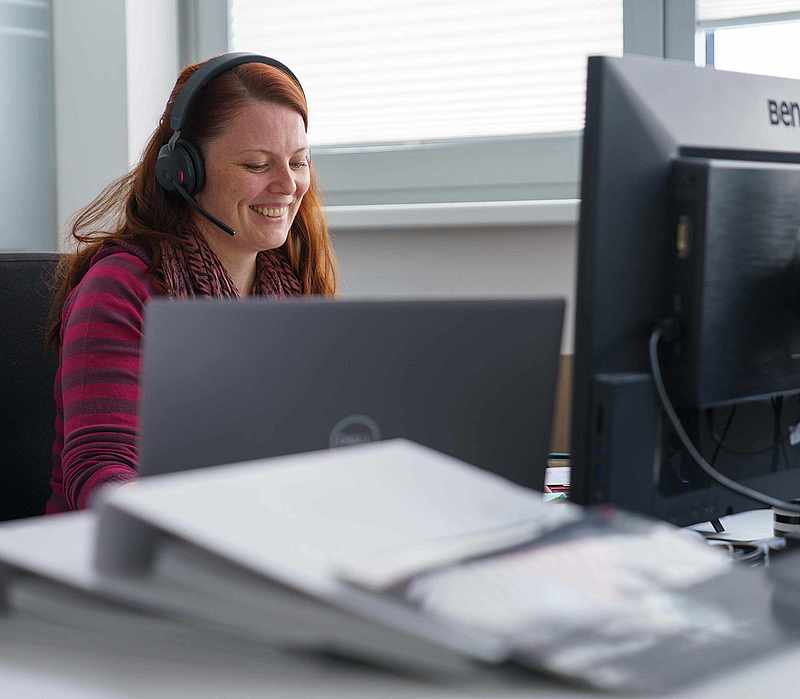 Kundenberaterin mit Headset am Schreibtisch